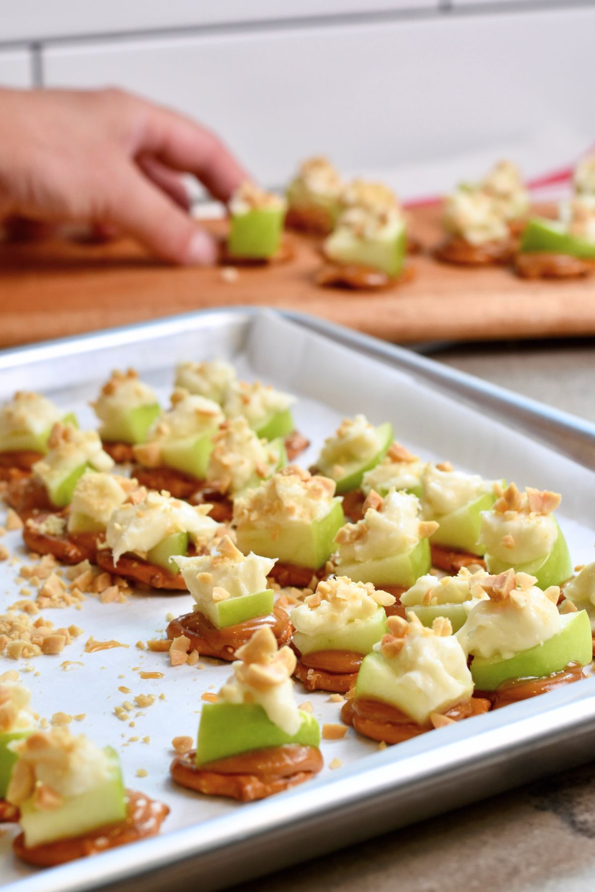 Place caramel apple bites on a wooden charcuterie board to serve to guests.