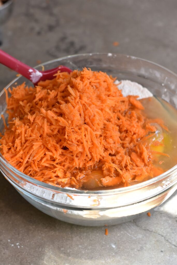 pour-the-shredded-carrots-into-the-mixing-bowl Add the shredded carrots into the mixture.