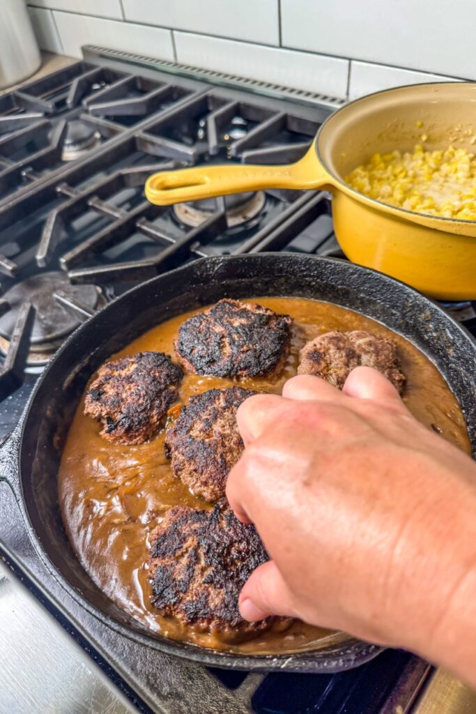 placing-the-hamburger-steaks-into-the-gravy-and-baking-in-the-oven Adding the burgers back into the pan with the gravy mixture.