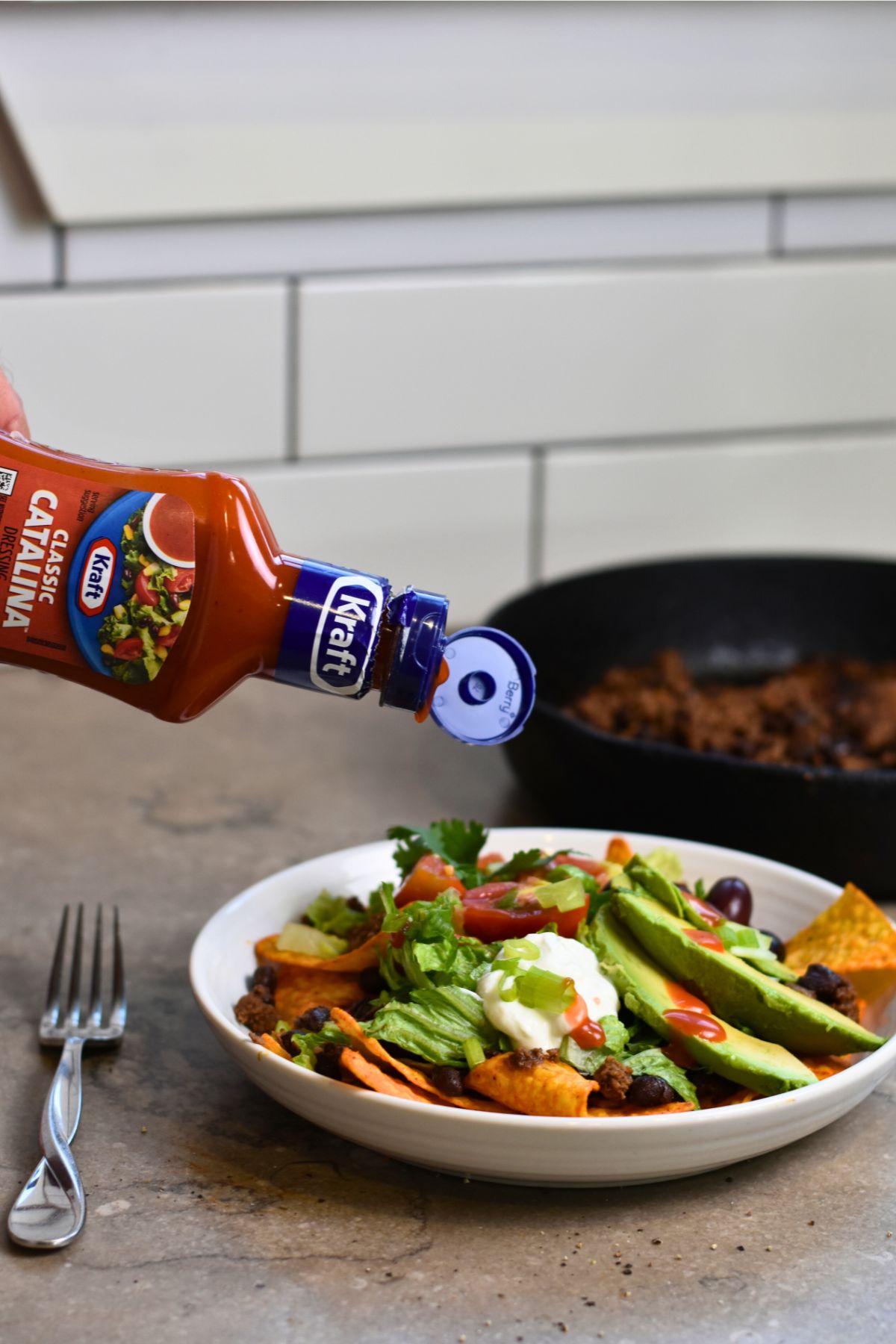 adding-catalina-dressing-to-the-top-of-the-taco-salad pouring-the-salad-dressing-on-top-of-the-taco-salad