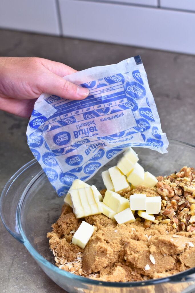 adding-the-cold-butter-to-the-mixture-for-the-crumble-topping Adding the cold butter to the brown sugar and oats mixture.