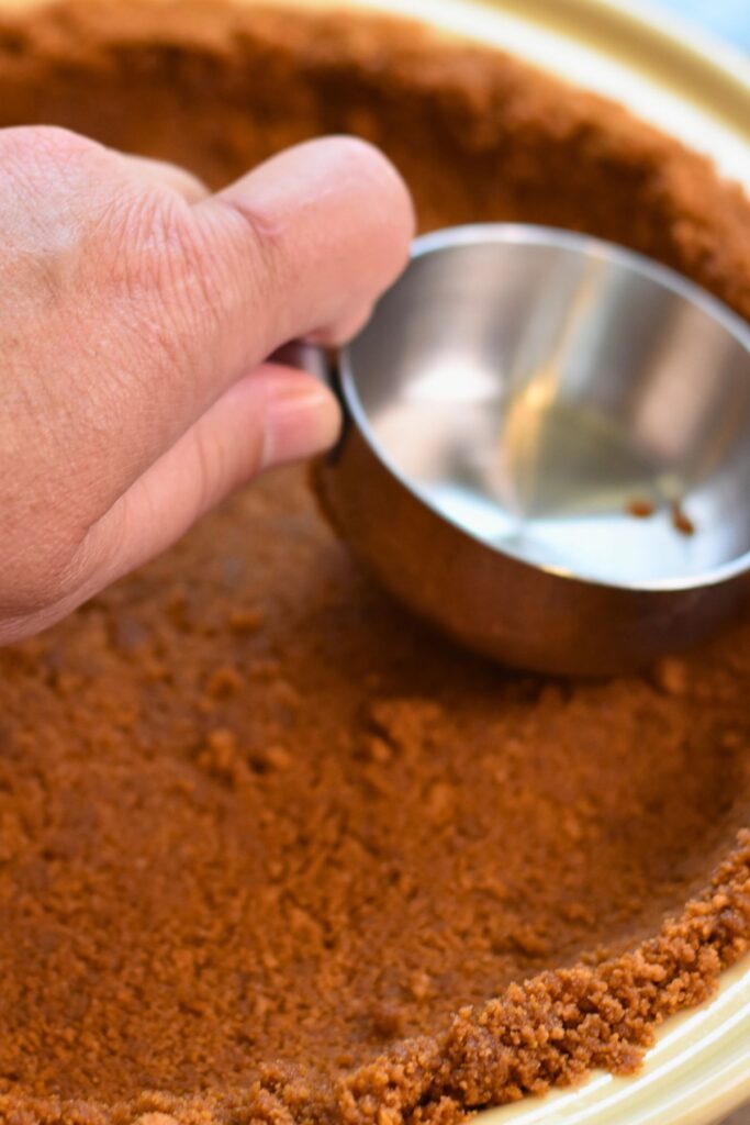 pressing-the-pie-crust-together pressing the mixture down with the back of a measuring cup.