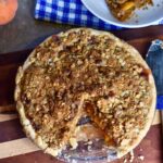 finished peach pie with homemade crumble topping served to guest.