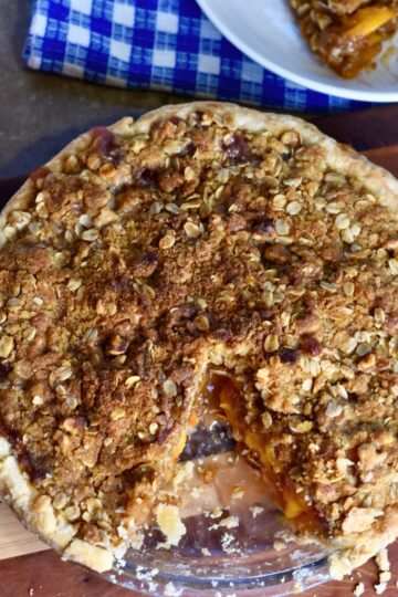 finished peach pie with homemade crumble topping served to guest.