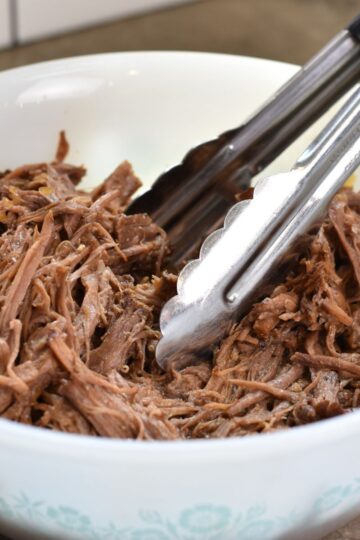 Juicy shredded beef in a white bowl.