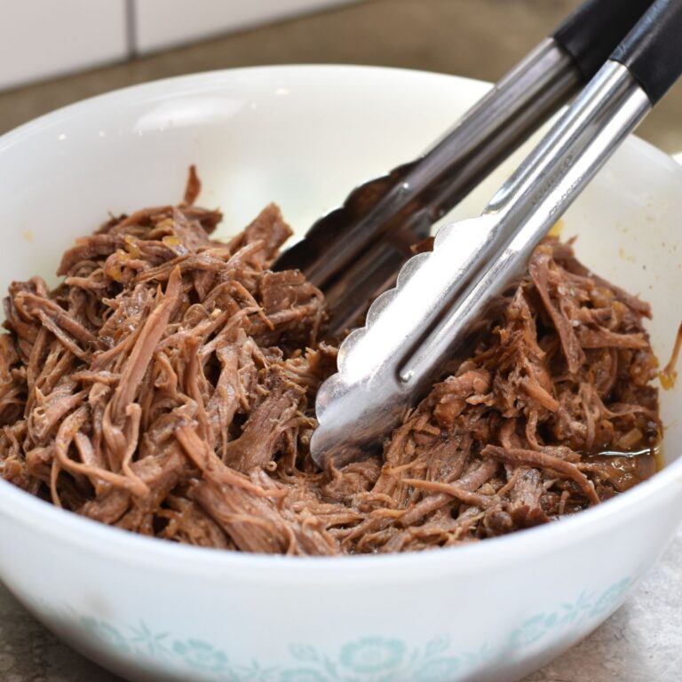 Juicy shredded beef in a white bowl.
