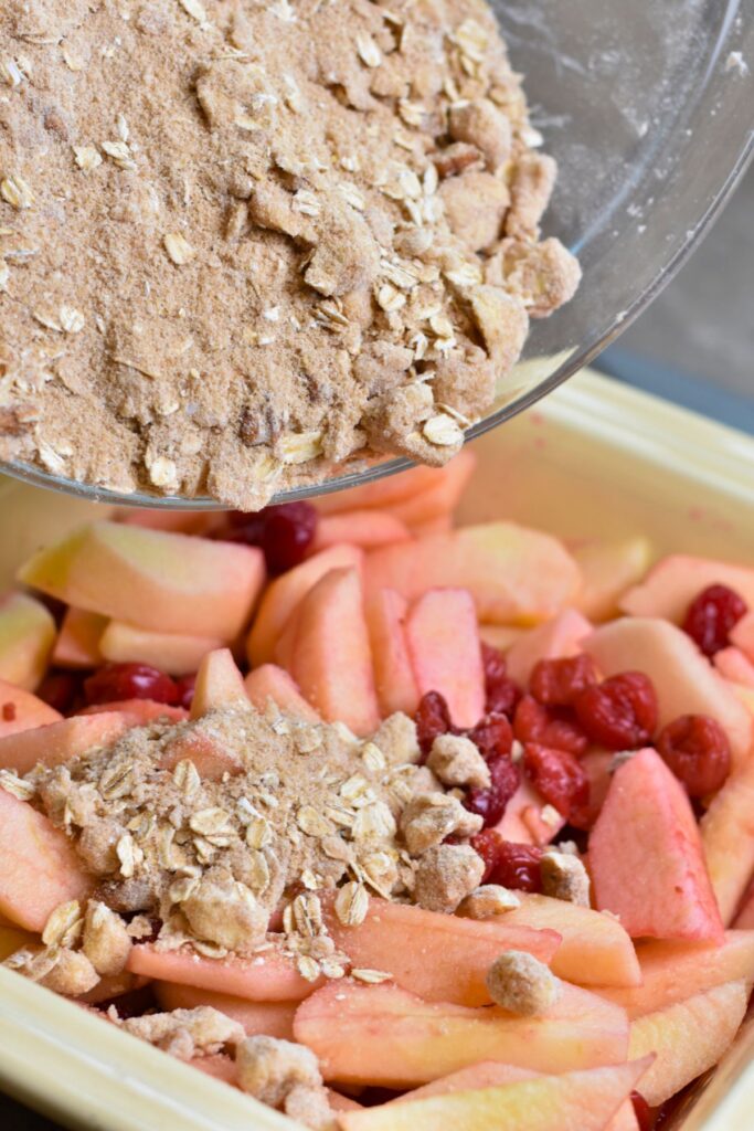 Adding the crumble mixture to the apple and cherries.