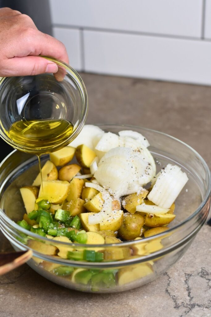 adding-olive-oil-on-top-of-the-potato-mixture adding the olive oil into the bowl for brats and potatoes.