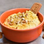 Topping the pumpkin dip with brown sugar and chopped pecans.