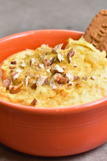 Topping the pumpkin dip with brown sugar and chopped pecans.