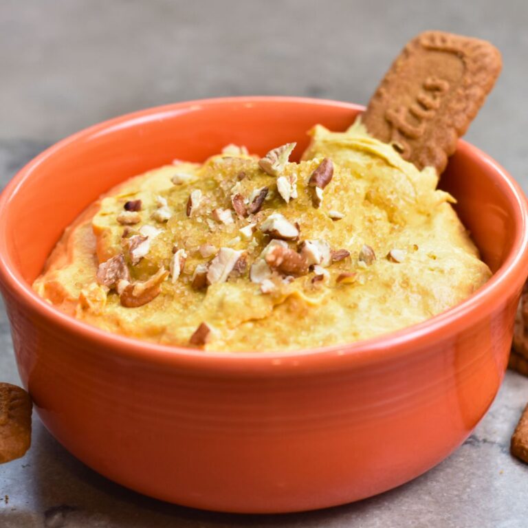 Topping the pumpkin dip with brown sugar and chopped pecans.