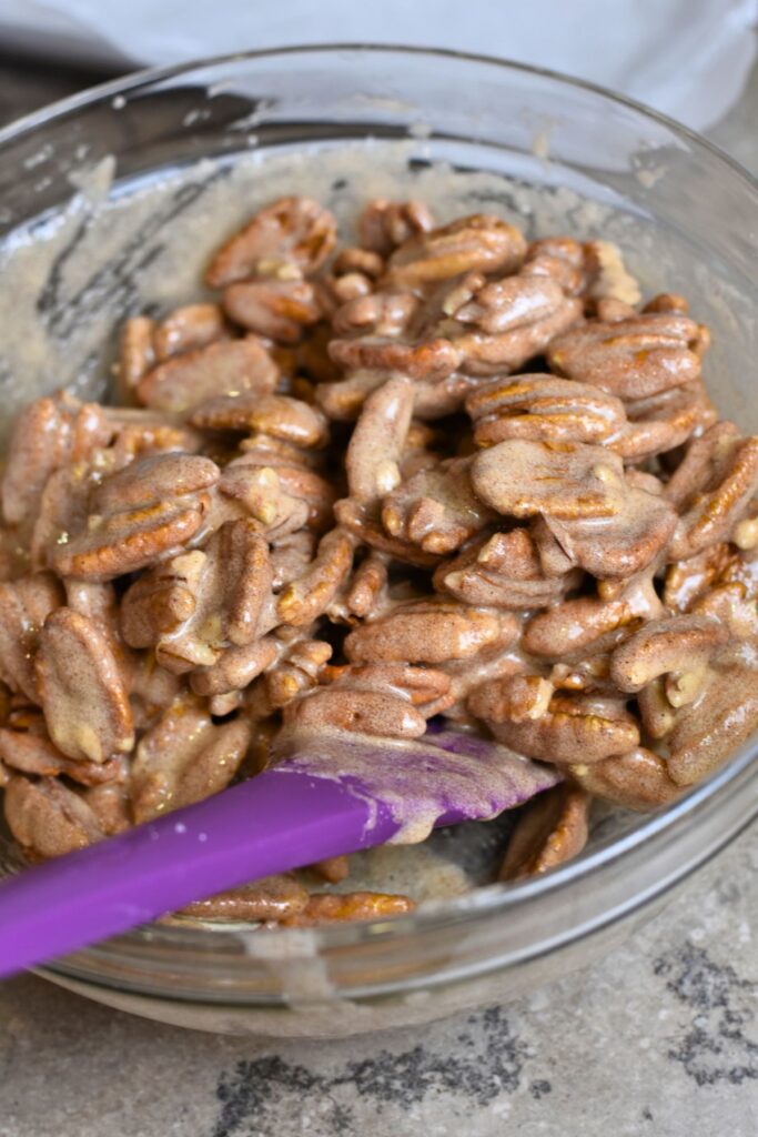 add-the-pecans-to-the-egg-mixture-and-then-mix-until-well-combined Mixing the egg white mixture onto the pecans.