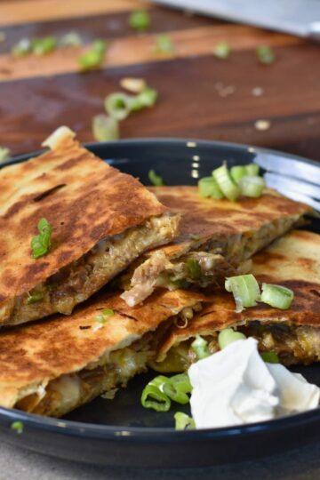 Serving the melty pulled pork quesadilla with sour cream.