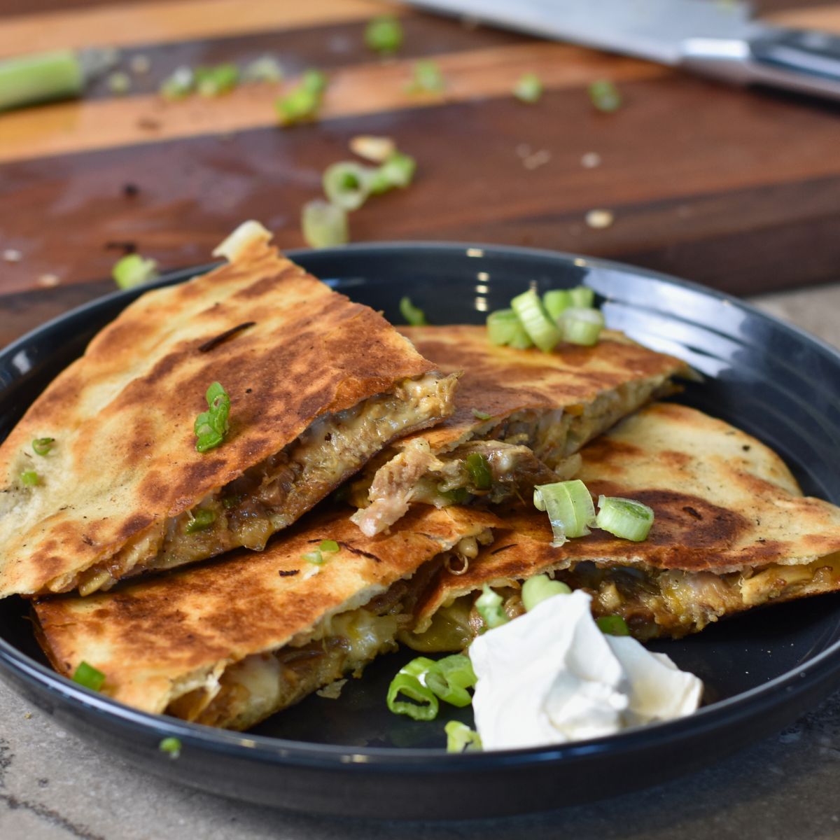 Serving the melty pulled pork quesadilla with sour cream.
