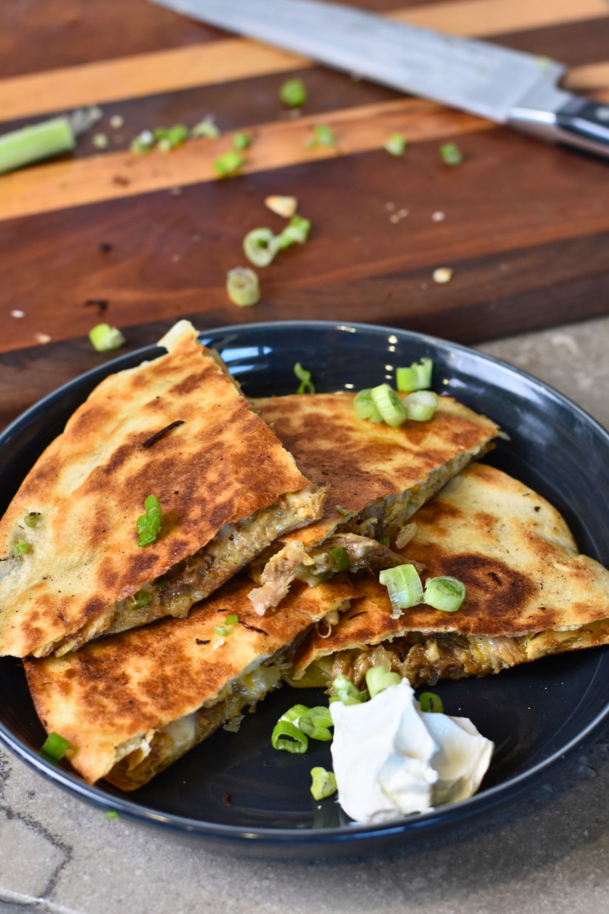 Golden-brown-quesadilla serving the pulled pork quesadilla with green onions on top.