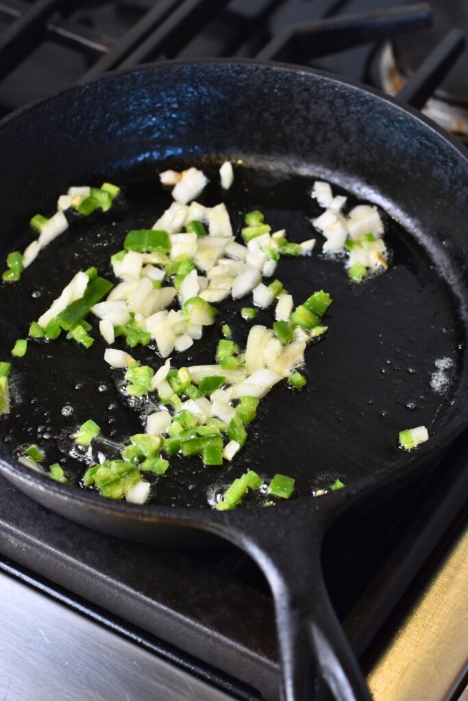 Cooking-the-onions-and-jalapenos-in-a-pan Cook the jalapeños and onions in the cast-iron with butter.