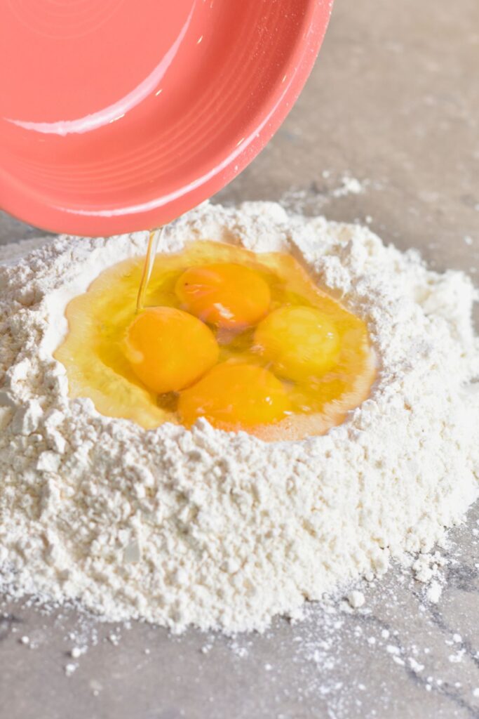 Pour-all-four-eggs-into-the-flour Adding farm-fresh eggs to my well of flour.