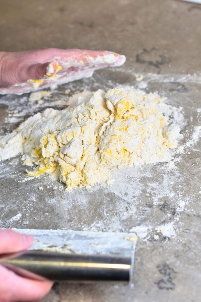 Use-a-bench-scraper-to-combine-the-flour-and-eggs-together Mixing the four and farm-fresh eggs with a bench scraper.