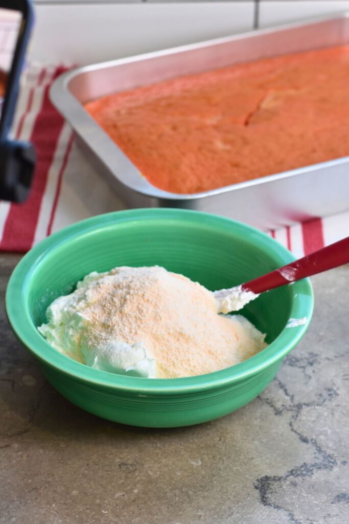 Bowl-of-whipped-topping-and-pudding-mix-for-frosting Green bowl with whipped topping and instant vanilla pudding mix ready to be mixed.