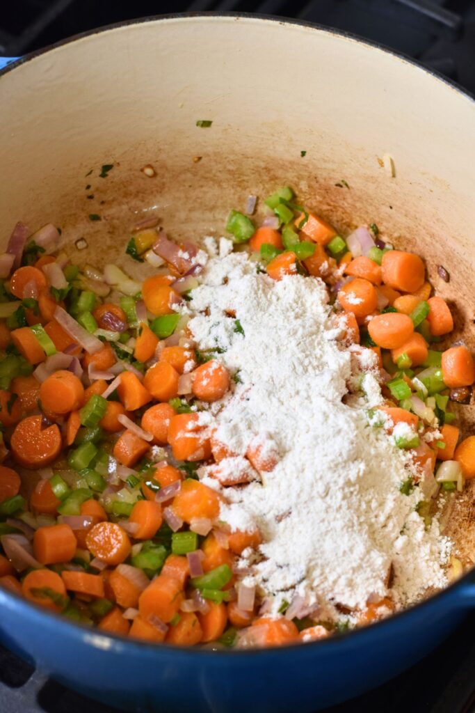 thickening-the-gravy-with-flour Add flour to the vegetable mixture to create a gravy.
