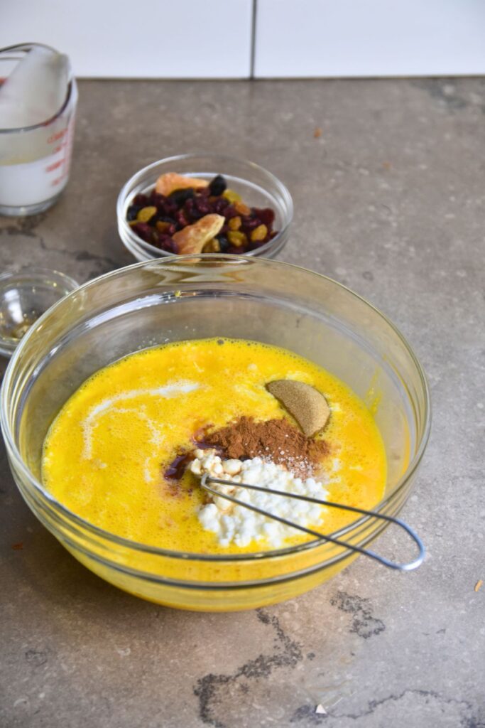 add-the-cottage-cheese-brown-sugar-and-other-ingredients-into-the-eggs-and-mix-until-well-combined Mixing all of the ingredients together for croissant breakfast casserole.