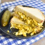 Dill pickle egg salad served on white fluffy bread.