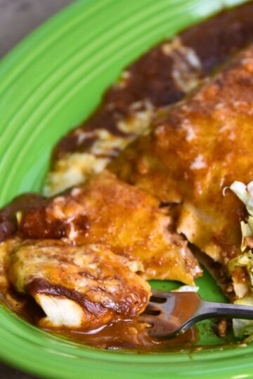 Eating the burrito enchilada with lettuce and a tomato.