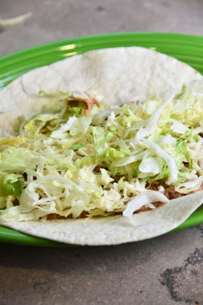 put-beans-ground-meat-cheese-and-lettuce-into-the-burrito Sprinkle the lettuce in the burrito.