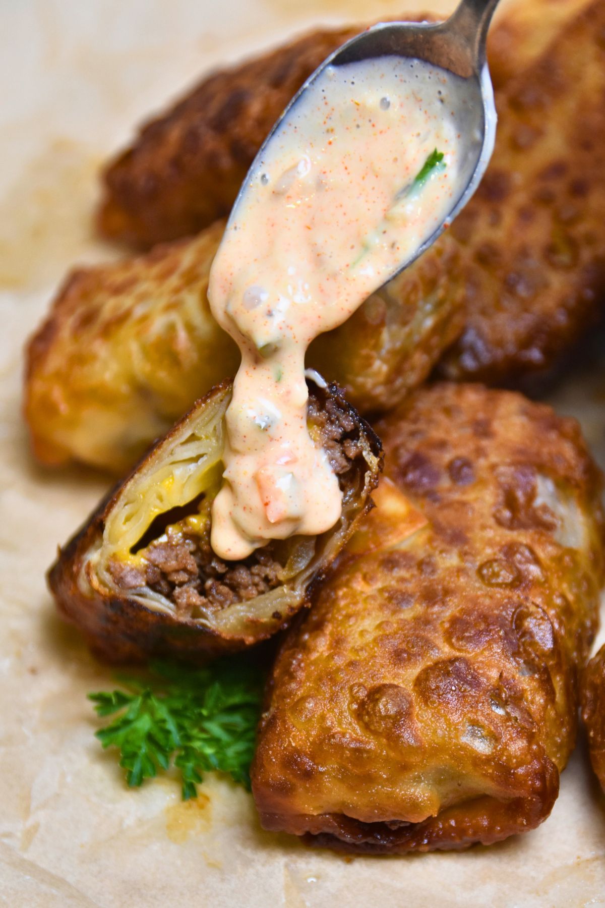 Pouring-on-big-mac-sauce Using a spoon to pour Big Mac sauce on a cheeseburger spring roll.