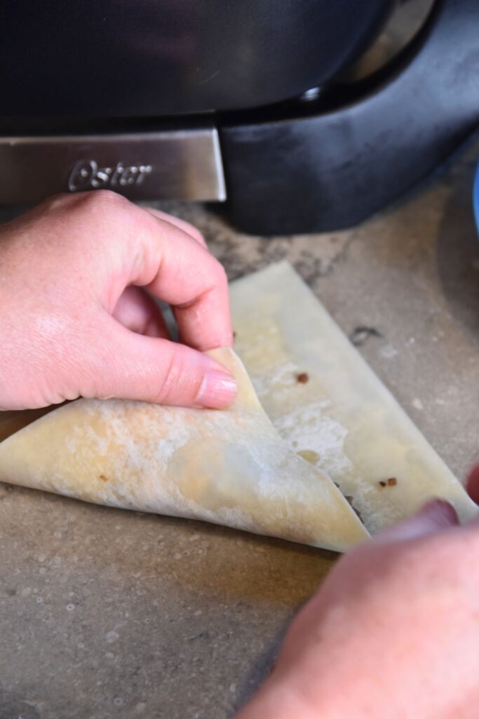 Fold-the-spring-roll-wrapper-into-a-triangle-shape-the-fry Fold the wonton into a triangle shape.