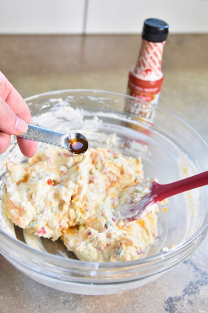 Stir-in-liquid-smoke-to-jalapeno-pimeto-cheese Adding a teaspoon of liquid smoke to the mixture.