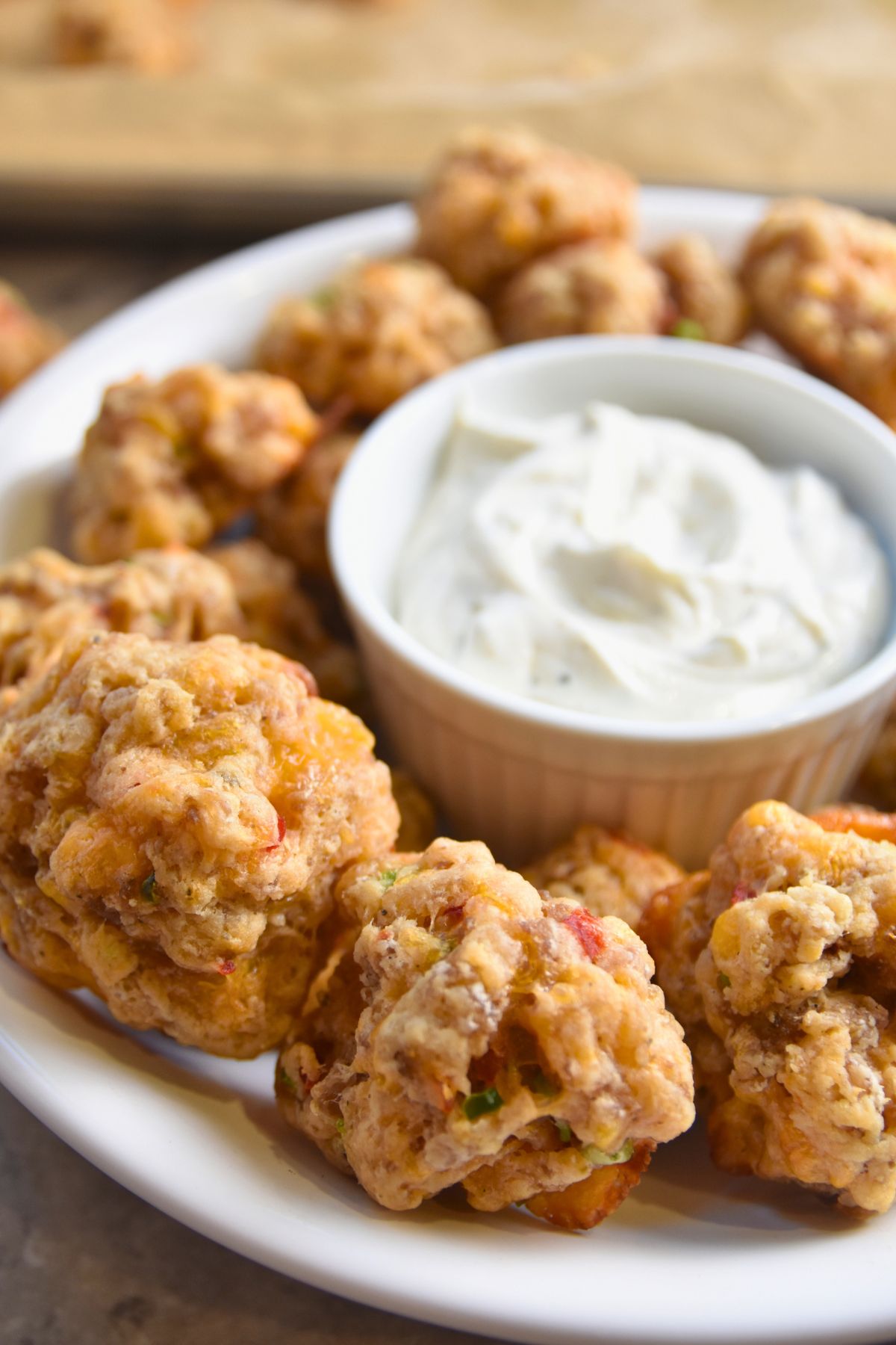 crsipy-pimento-cheese-sausage-balls-served-on-a-white-plate Serving pimento cheese sausage balls to party guest.