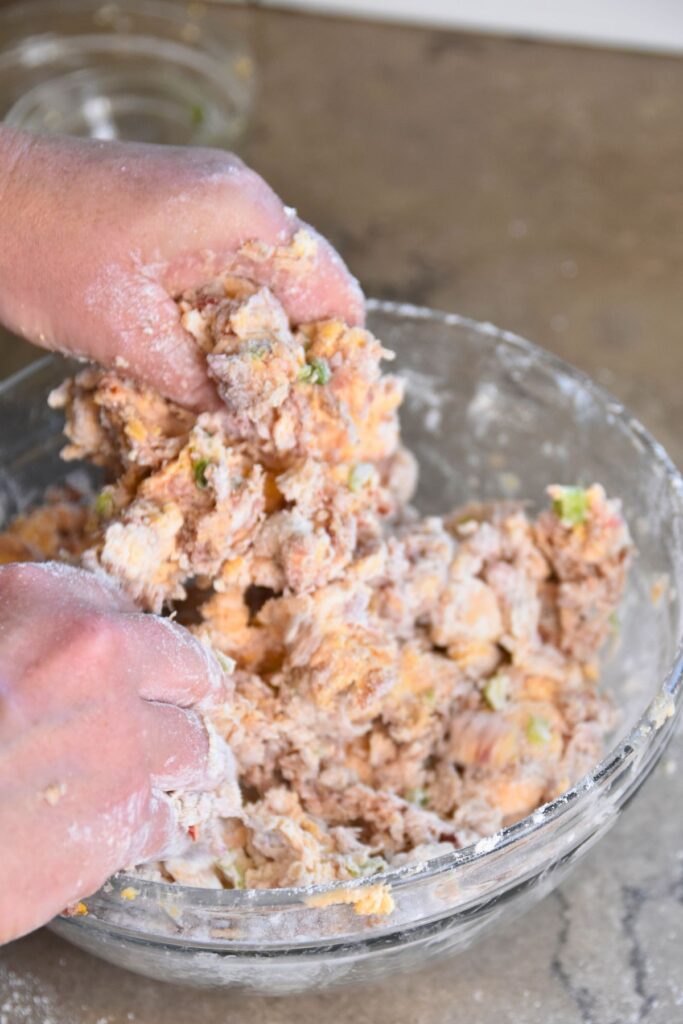 mixing-pimento-cheese-sausage-balls-in-a-glass-bowl Smash the pimento cheese sausage ball mixture together with your hands.