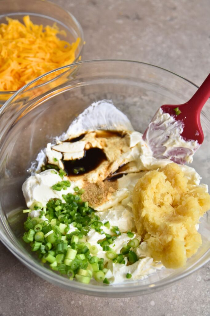 mix-the-cream-cheese-pineapple-and-green-onions-together Mixing the ingredients in a large glass bowl.