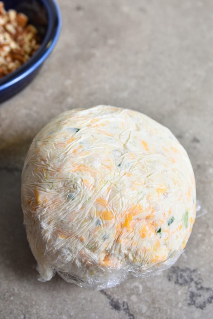 Cover-the-pineapple-cheese-ball-with-plastic-wrap Cover the cheese ball with plastic wrap and refrigerate.