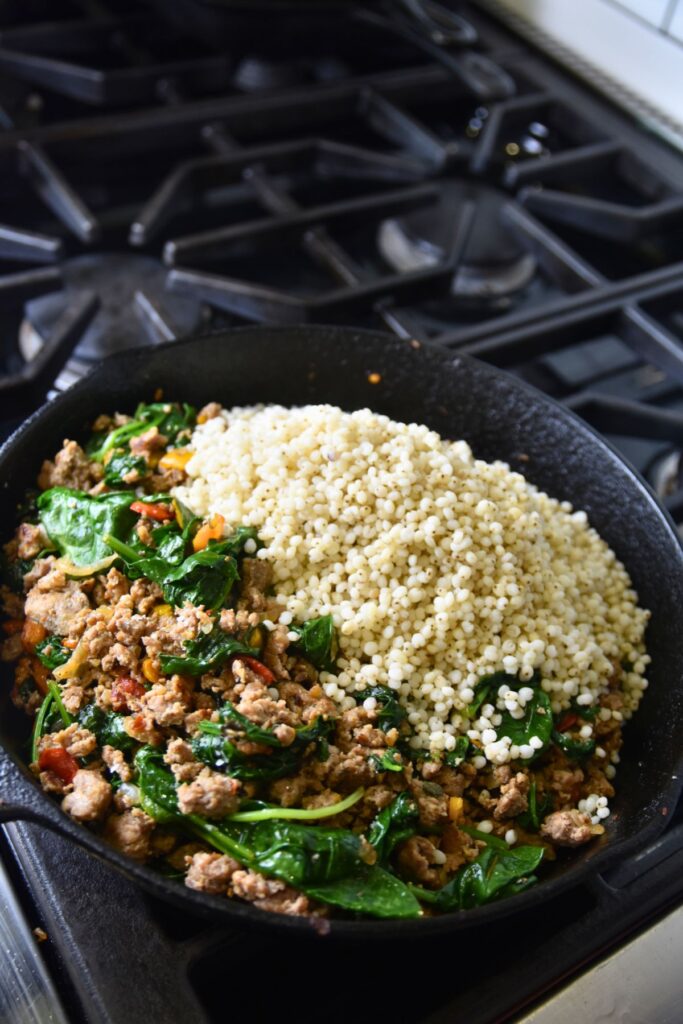 pour-the-pearled-sorghum-into-your-skillet Adding the sorghum to the skillet of sausage and spinach.