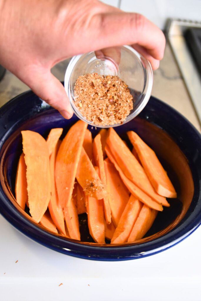 seasoning-sweet-potato-fries Sprinkle the seasoning mix on the sweet potato wedges.
