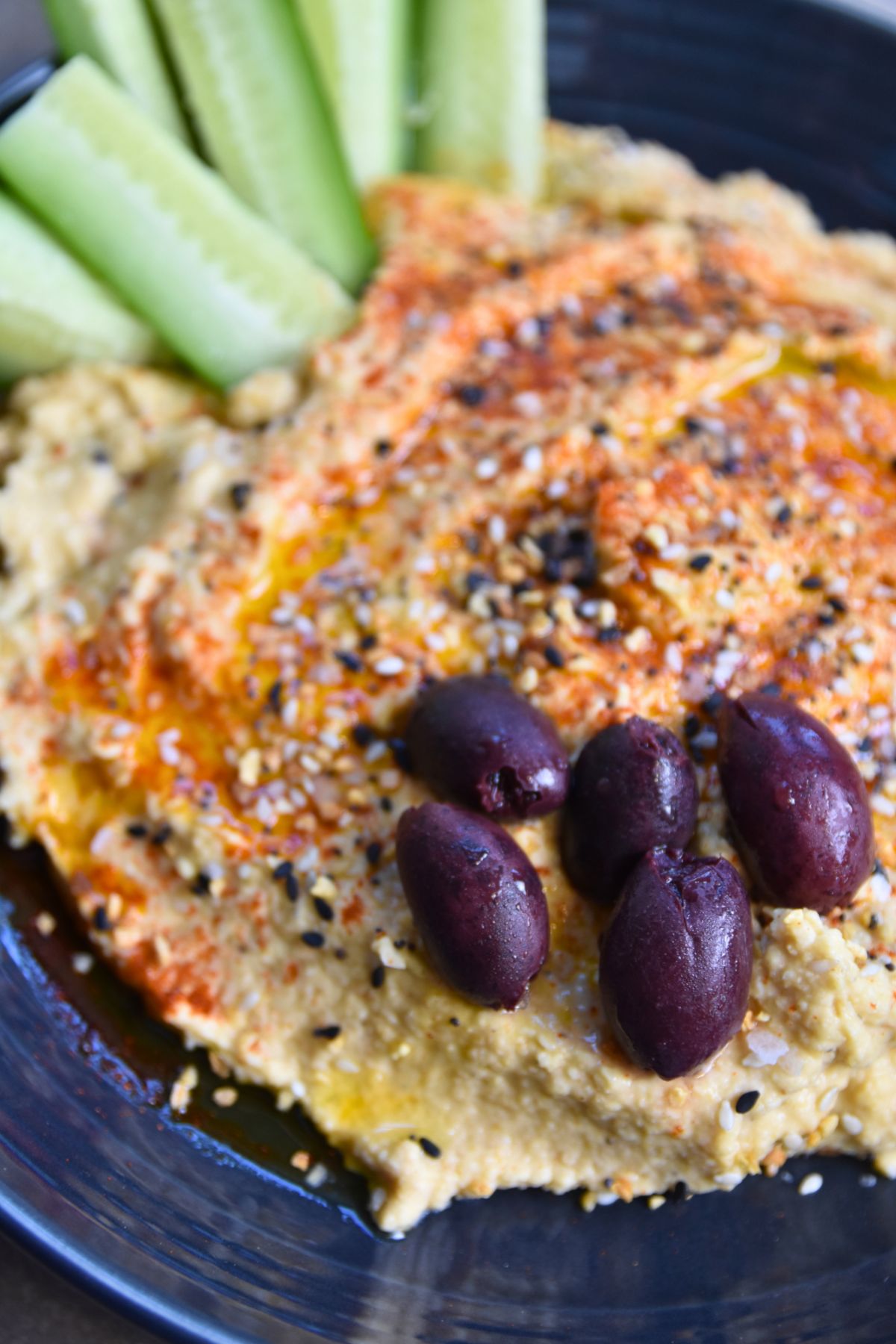 Topping-the-hummus-with-olives Hummus with everything bagel seasoning on top.
