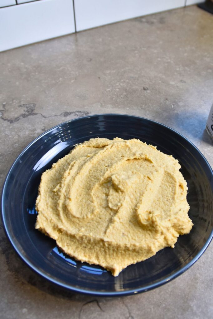scoop-the-hummus-out-of-the-food-processor-onto-a-serving-dish Spread a layer of hummus in your serving bowl.