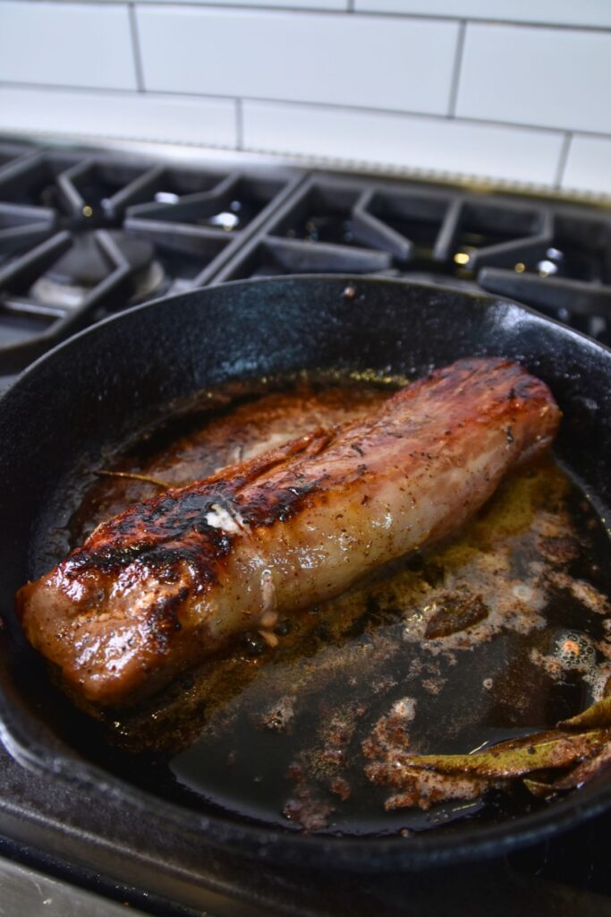 Searing-the-pork-tenderloin-in-a-cast-iron-skillet Sear the pork tenderloin until golden brown on each side.