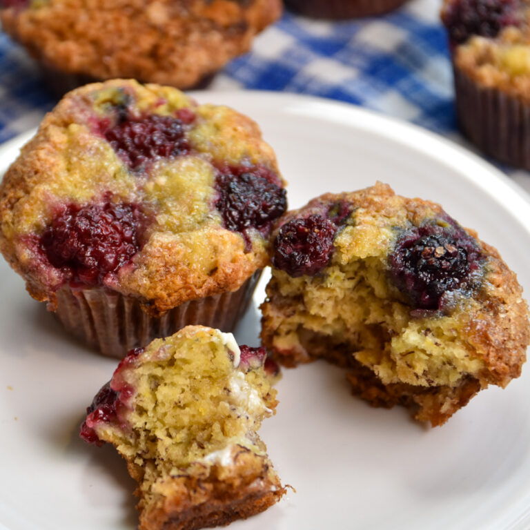 two blackberry banana muffins on white plate