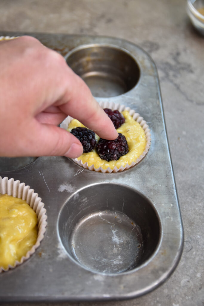 pressing blackberries into muffin batter