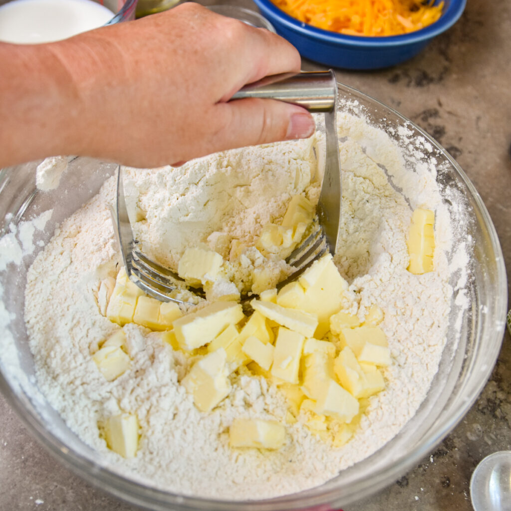 Using a pastry blender to cut butter into biscuit mix.