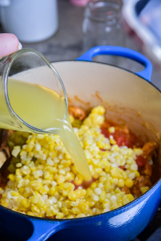 Adding broth to chicken enchilada soup.