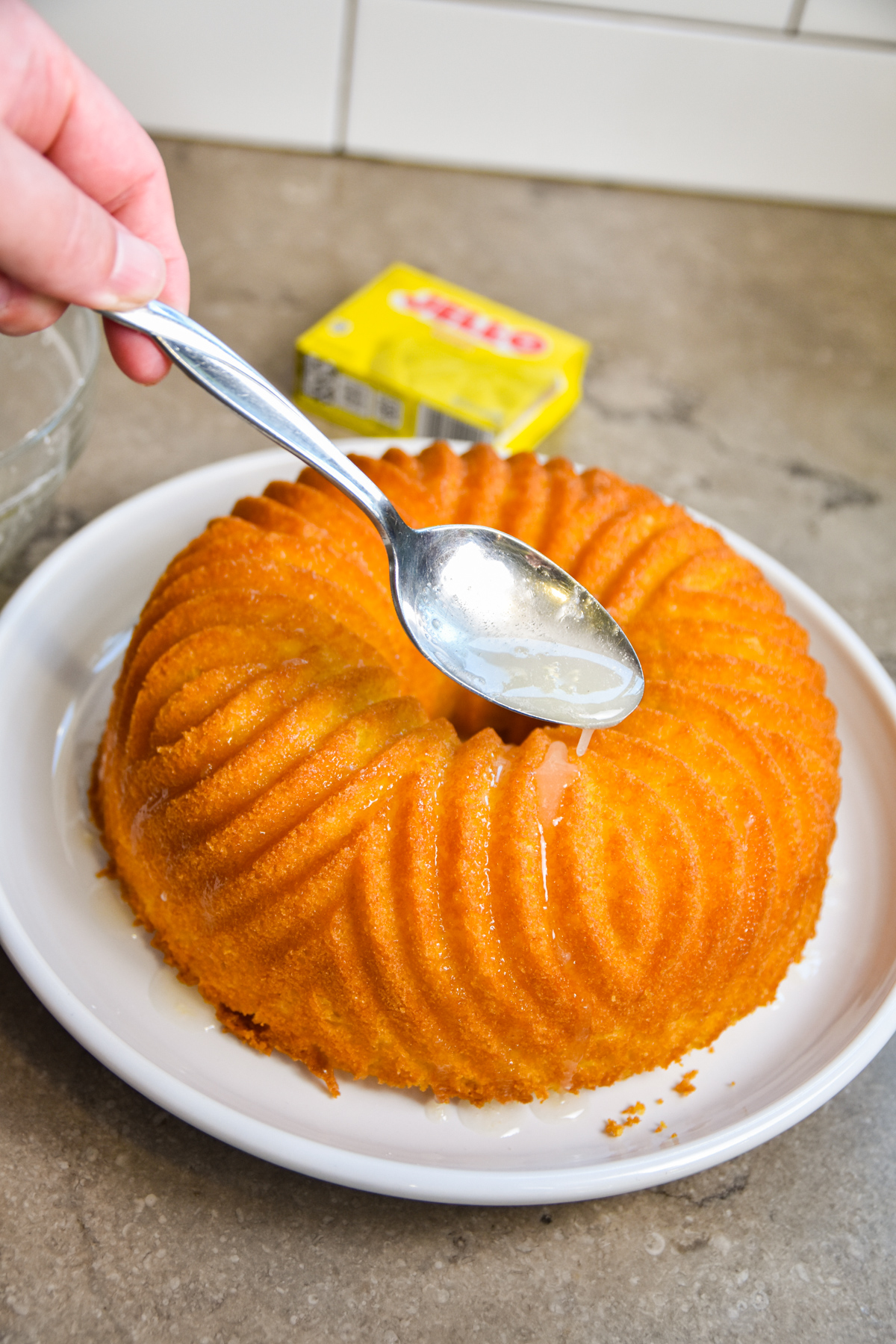 Spooning icing onto lemon jello cake.