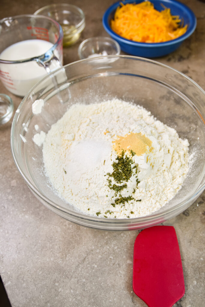 Adding ingredients to flour for cheddar bay biscuits.