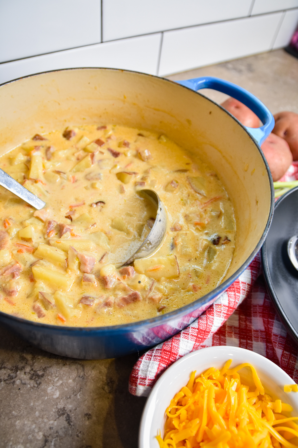 Pot of finished cheesy ham and potato soup with ladle.