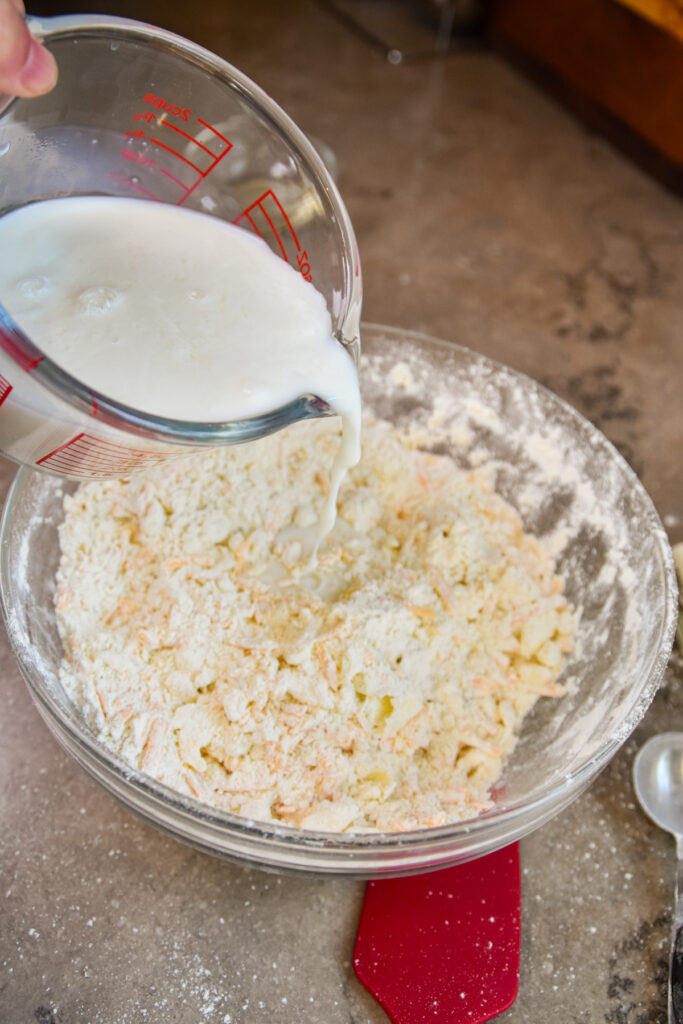 Adding buttermilk to bowl of biscuit mix.