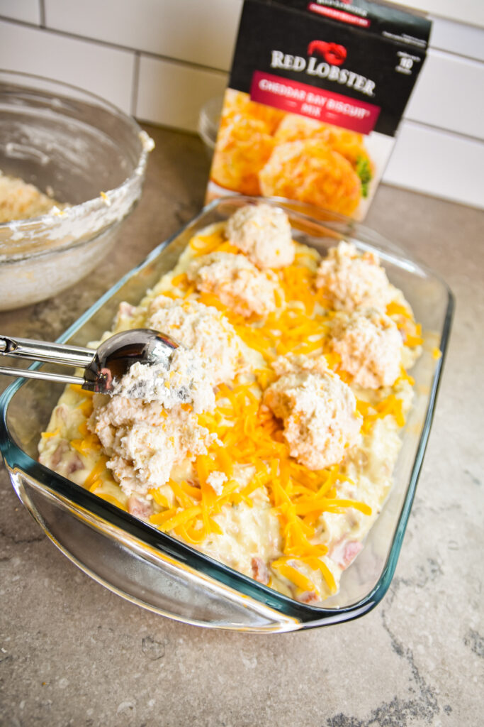 Adding scoops of biscuit dough onto casserole.