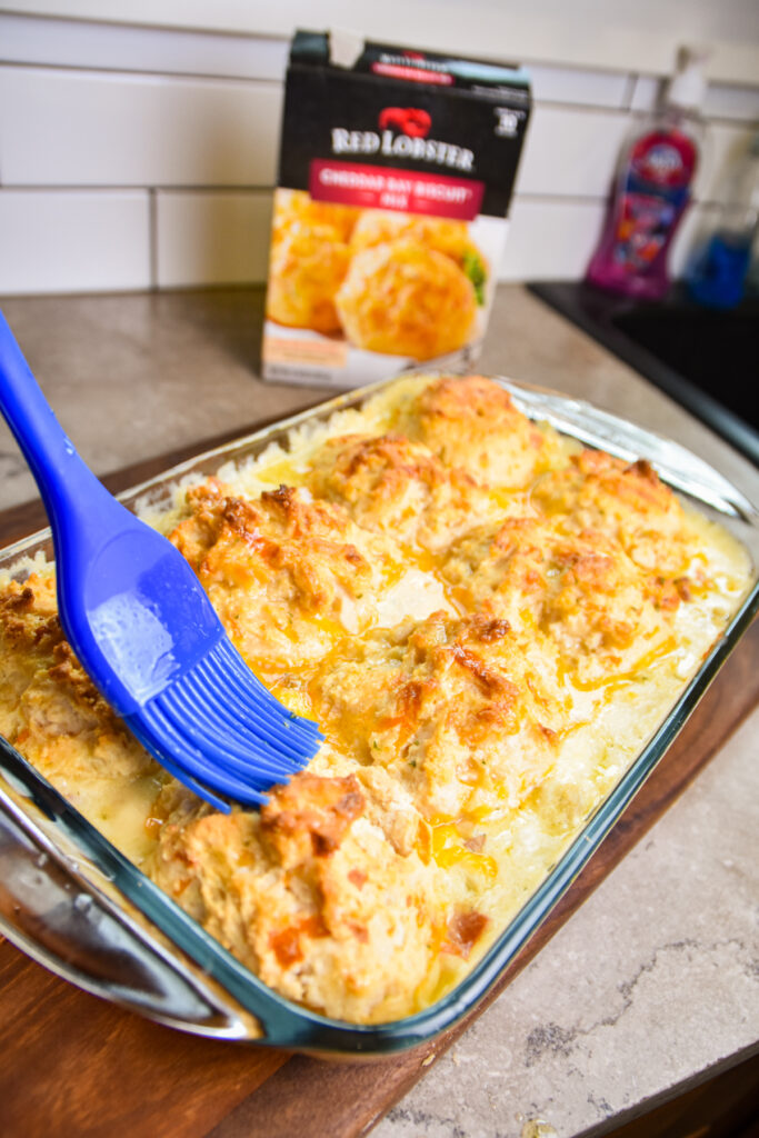 Brushing butter onto garlic biscuits for casserole.